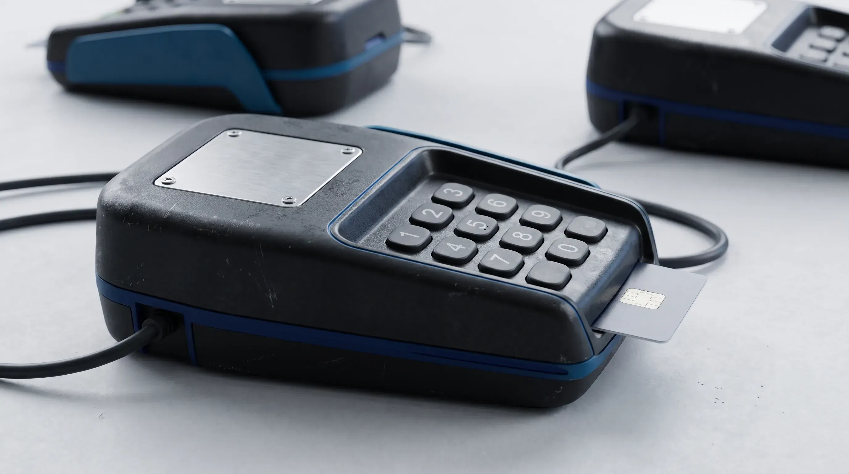 A realistic commercial payment HSM terminal with a chip card and keypad, illuminated by soft studio lighting against a neutral background.
