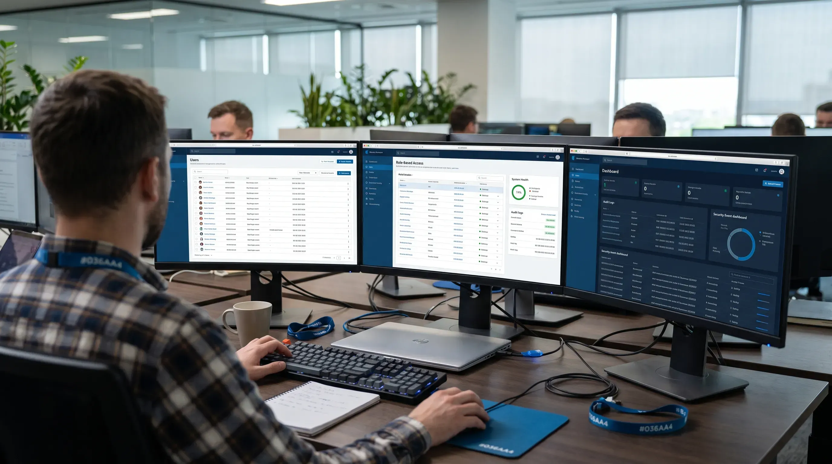 An enterprise security engineer analyzes identity and access management software on multiple monitors in a modern fintech office.